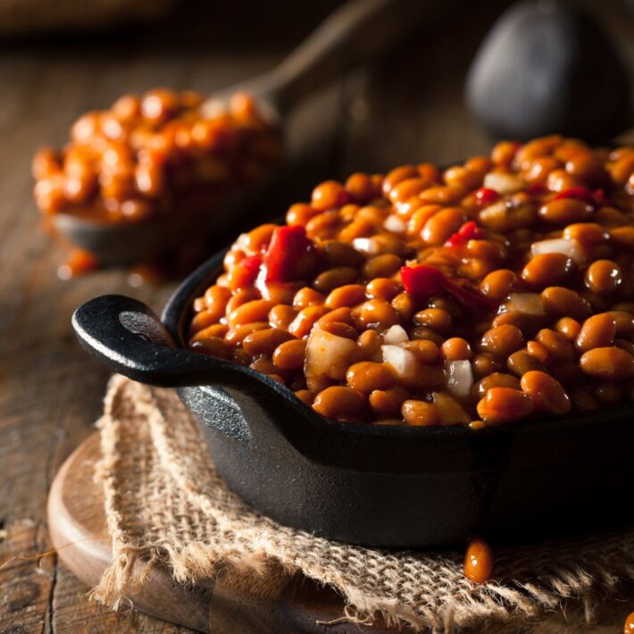 Tropical Baked Beans in a black cast iron skillet sitting on a brown placemat