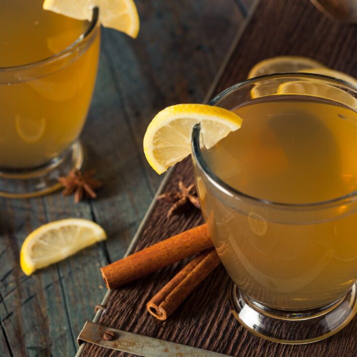 Hot Toddy With Passion Fruit Cocktail Recipe with lemon wedges and cinnamon sticks