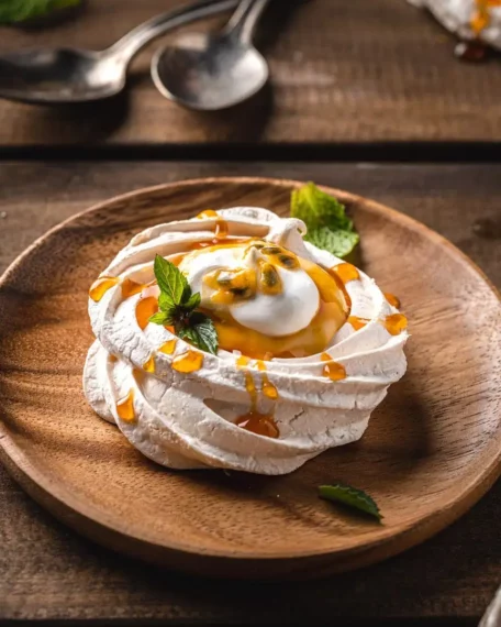 Pavlova Made With Passion Fruit sitting on a wooden plate